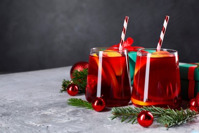 Photo of Delicious Sangria drink in glasses and Christmas decorations on grey textured table, closeup. Space for text