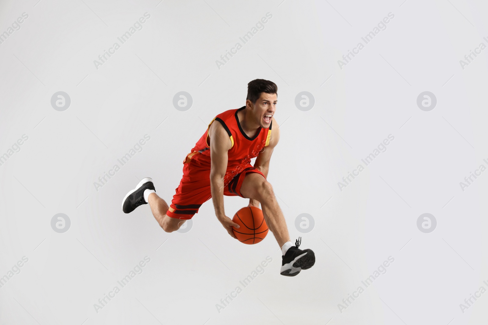 Photo of Professional sportsman playing basketball on grey background