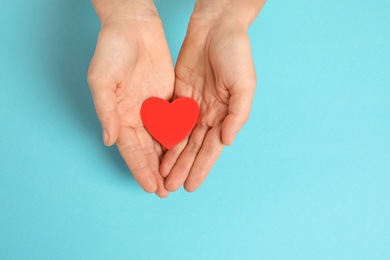 Photo of Woman holding paper heart on color background, top view with space for text