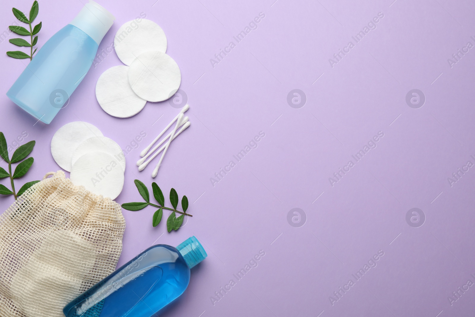 Photo of Cotton pads, swabs and makeup removal products on violet background, flat lay. Space for text