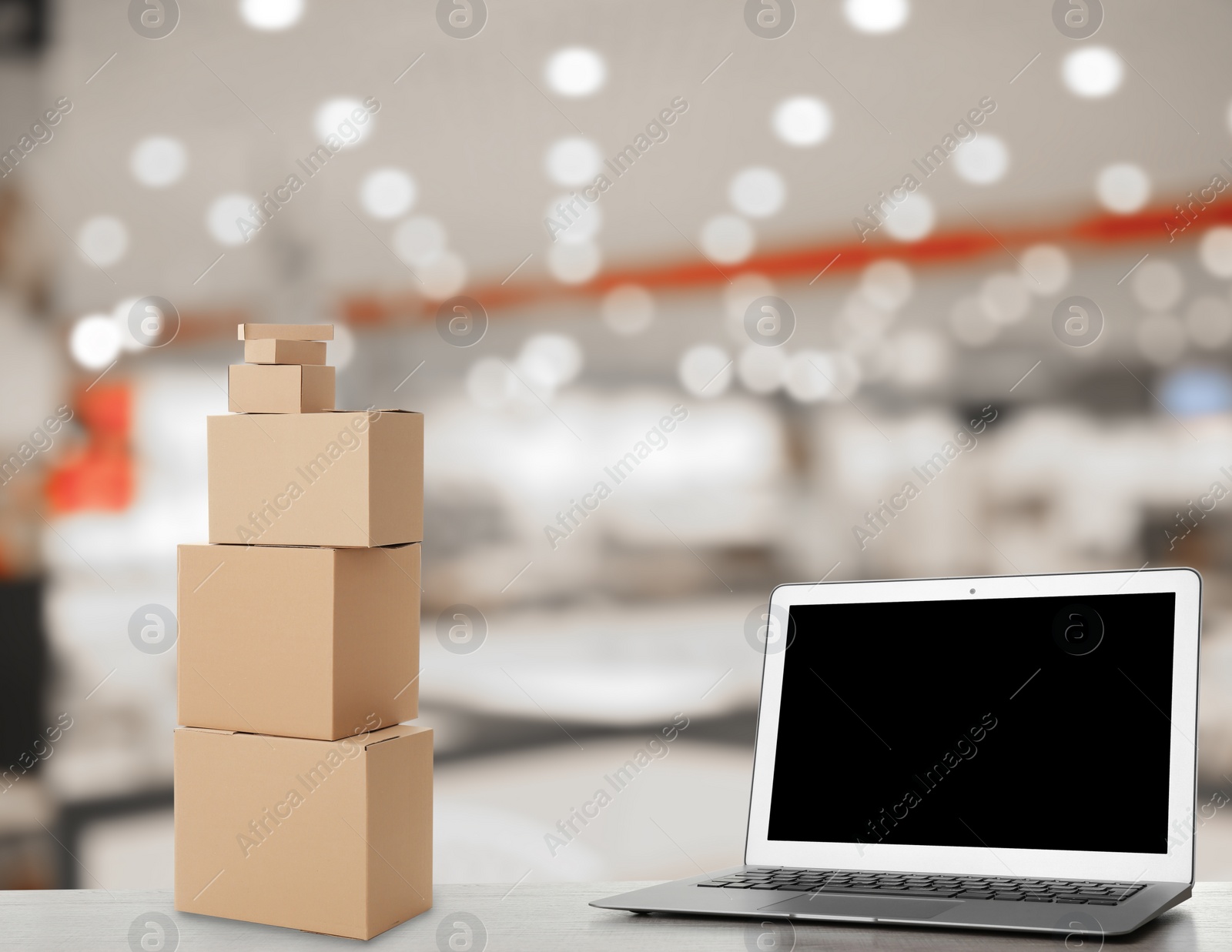 Image of Online selling. Laptop and parcels on table in store