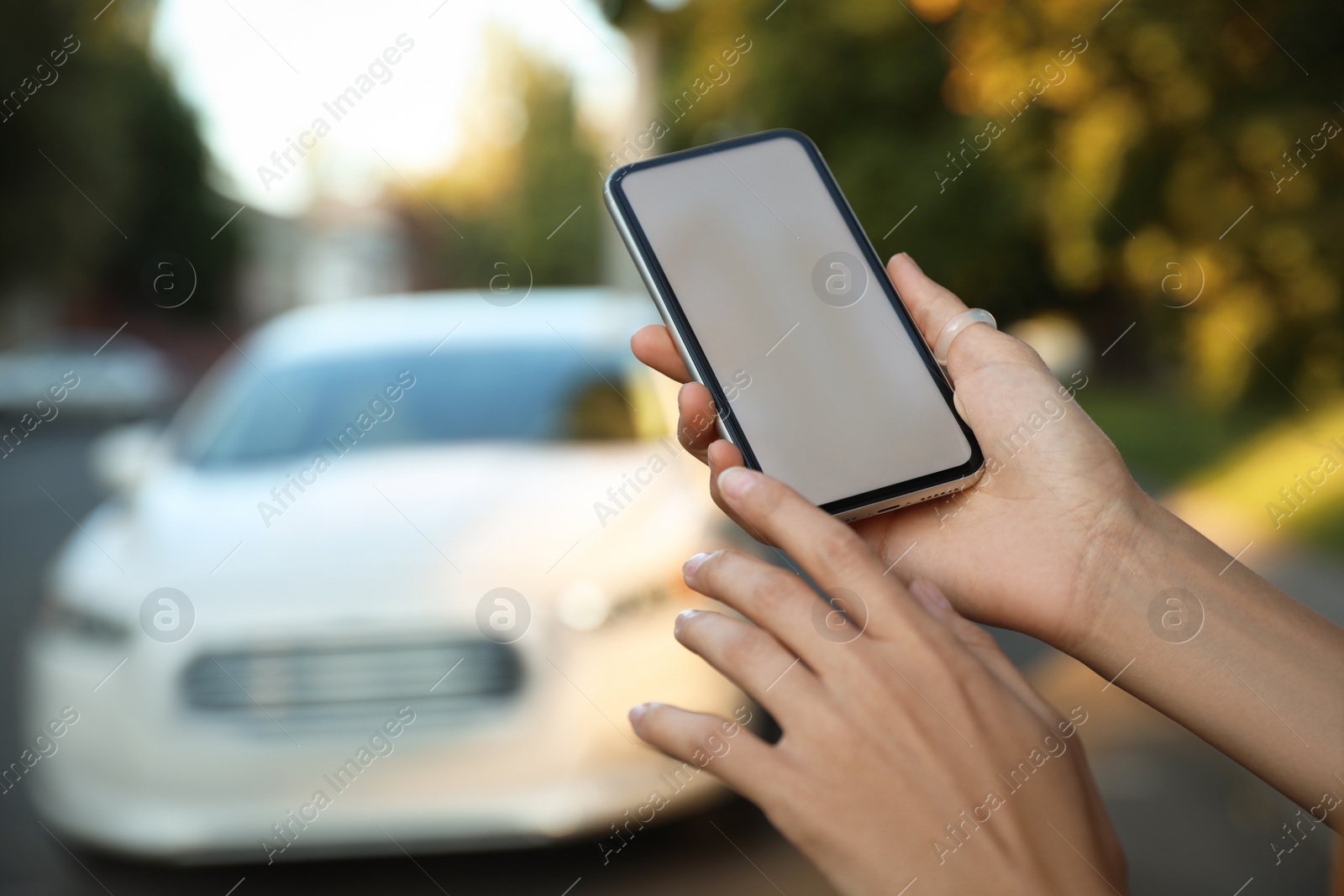 Photo of Woman ordering taxi with smartphone on city street, closeup