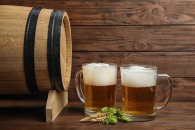 Photo of Composition with tasty beer and fresh green hops on wooden table