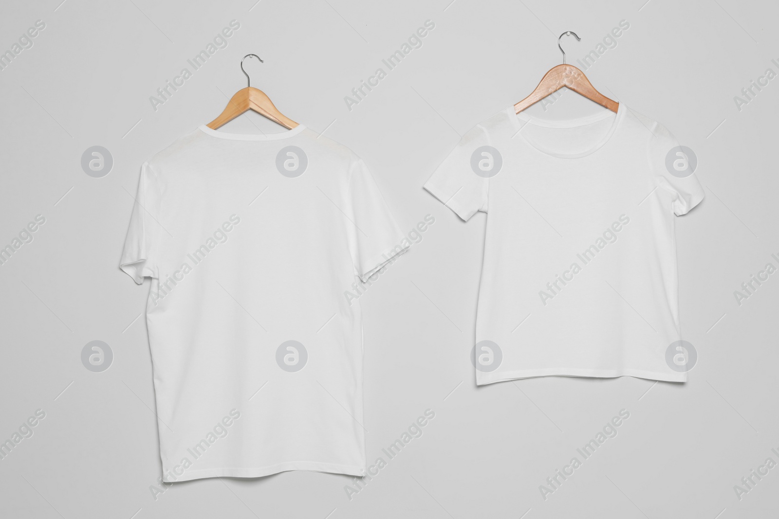 Photo of Hangers with blank t-shirts on gray background. Mock up for design