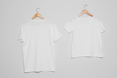 Hangers with blank t-shirts on gray background. Mock up for design