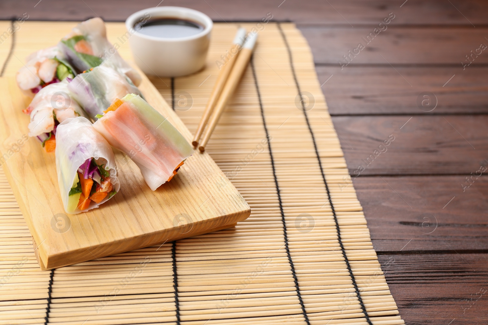 Photo of Delicious rolls wrapped in rice paper served on wooden table