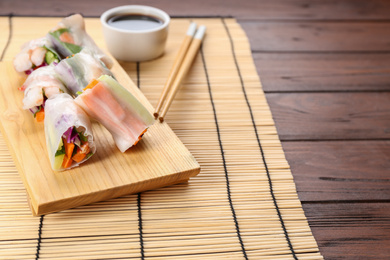 Photo of Delicious rolls wrapped in rice paper served on wooden table