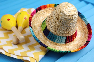 Mexican sombrero hat, towel and maracas on blue wooden surface