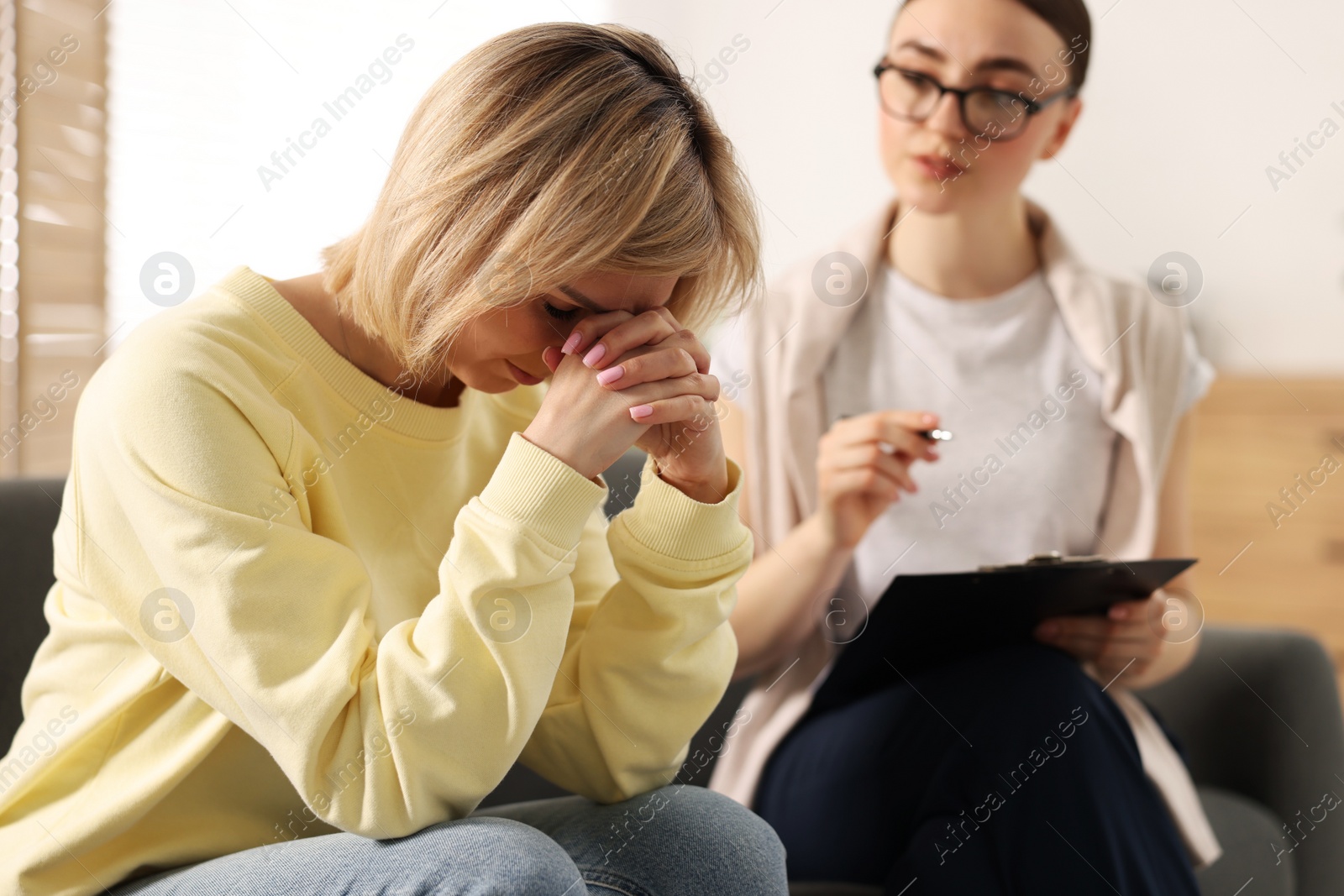 Photo of Professional psychotherapist working with on sofa patient in office