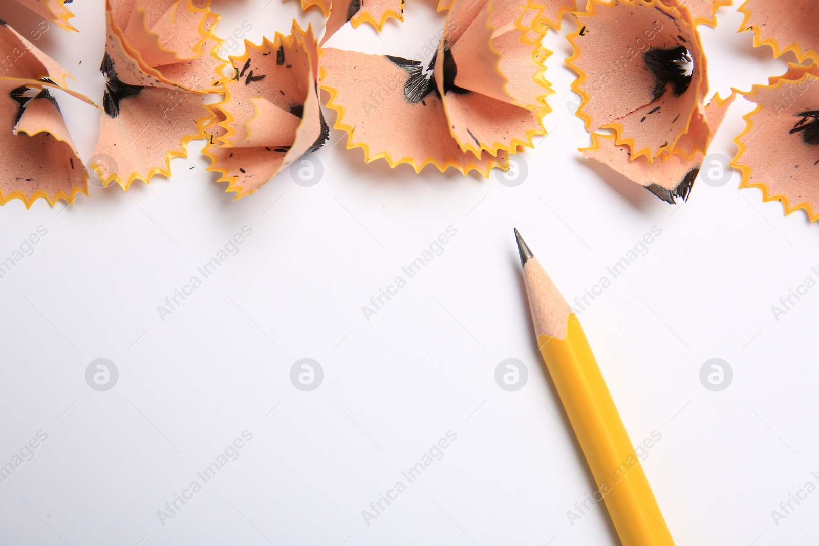 Photo of Sharp graphite pencil and shavings on white background, top view. Space for text