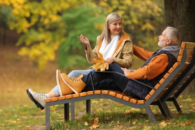 Photo of Affectionate senior couple with dry leaves spending time together in autumn park