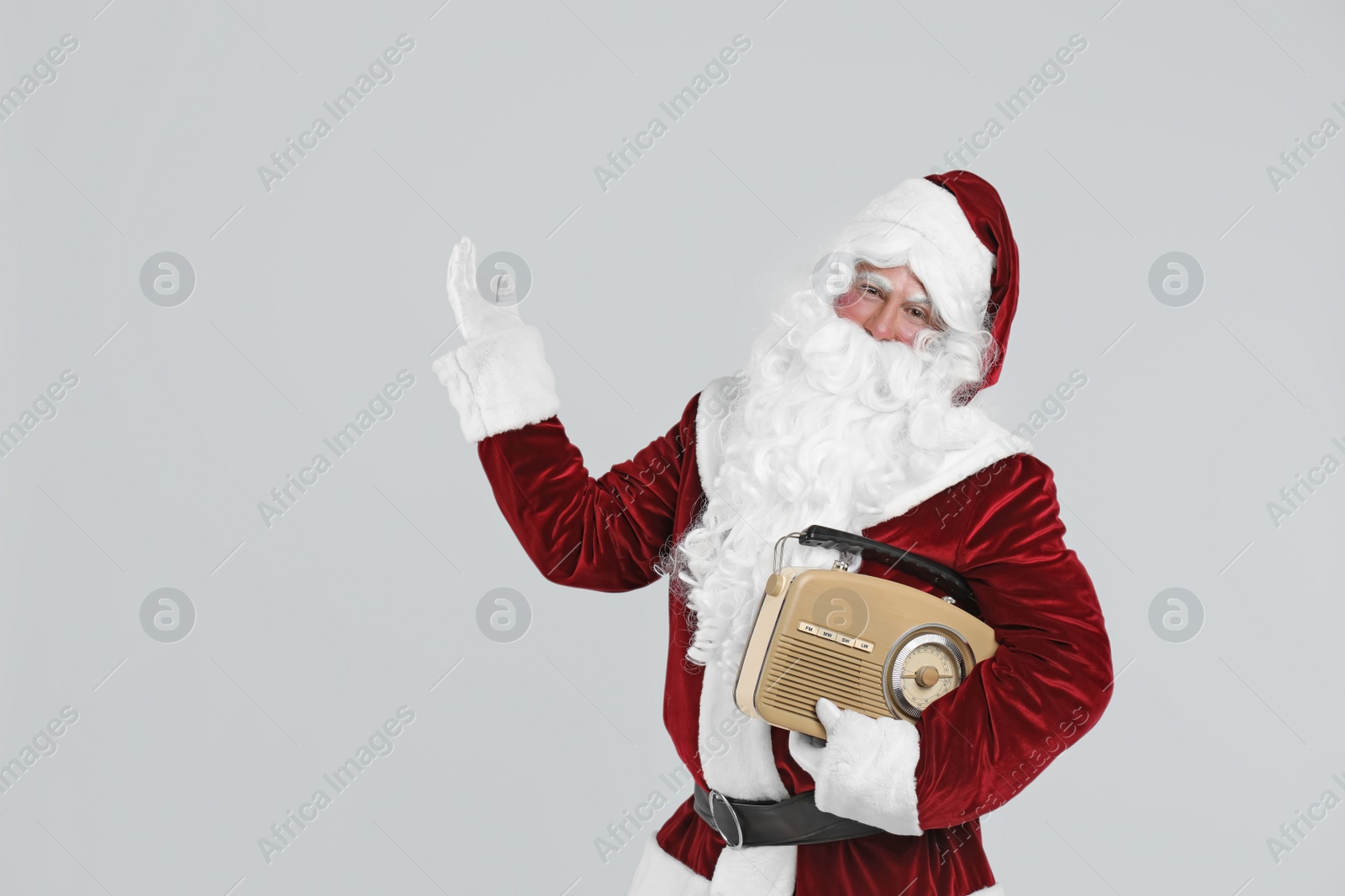 Photo of Santa Claus with vintage radio on light grey background. Christmas music