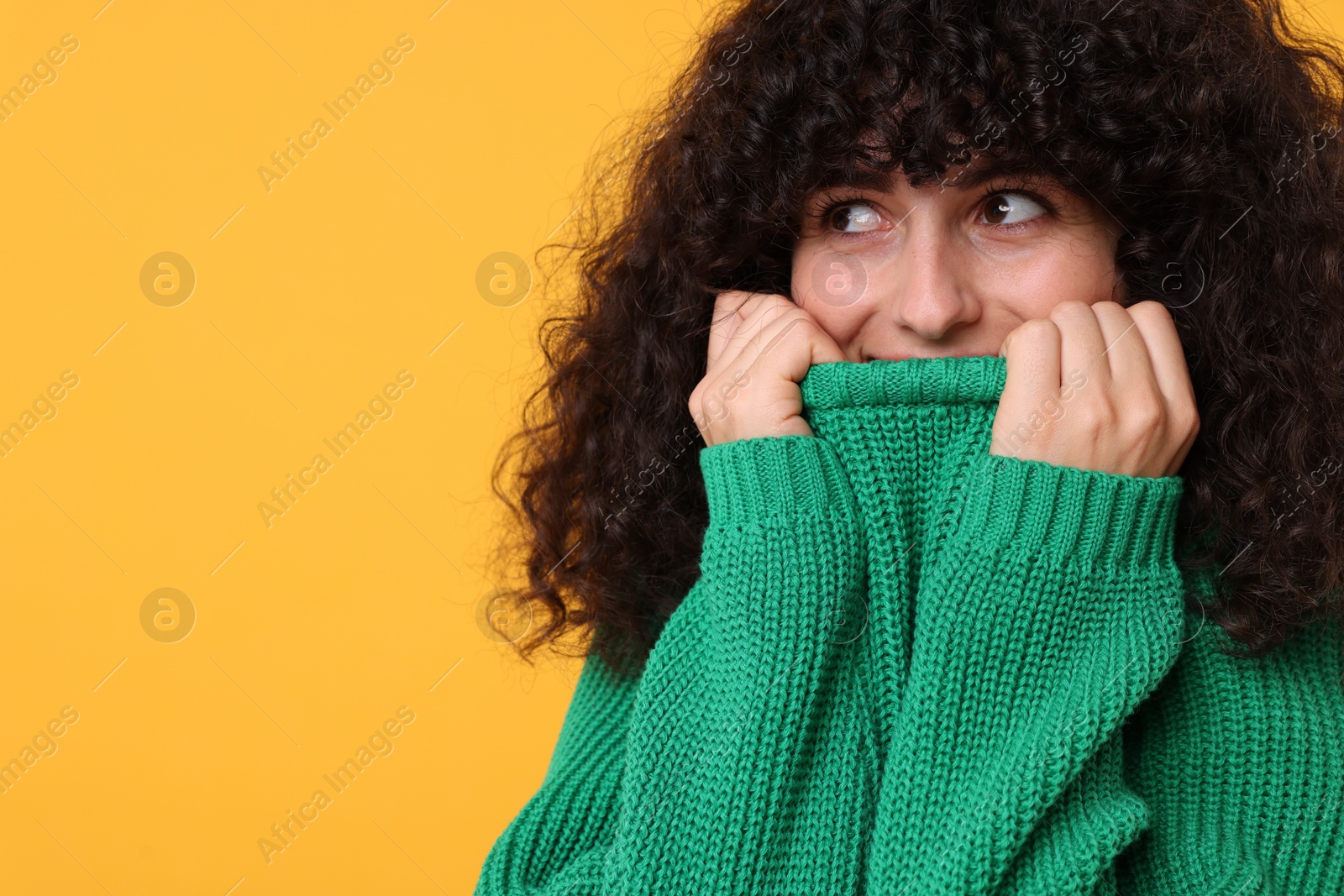 Photo of Young woman in stylish green sweater on yellow background, space for text