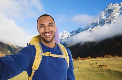 Happy tourist with backpack taking selfie in mountains