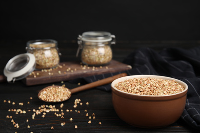 Photo of Bowl with green buckwheat on black wooden table. Space for text