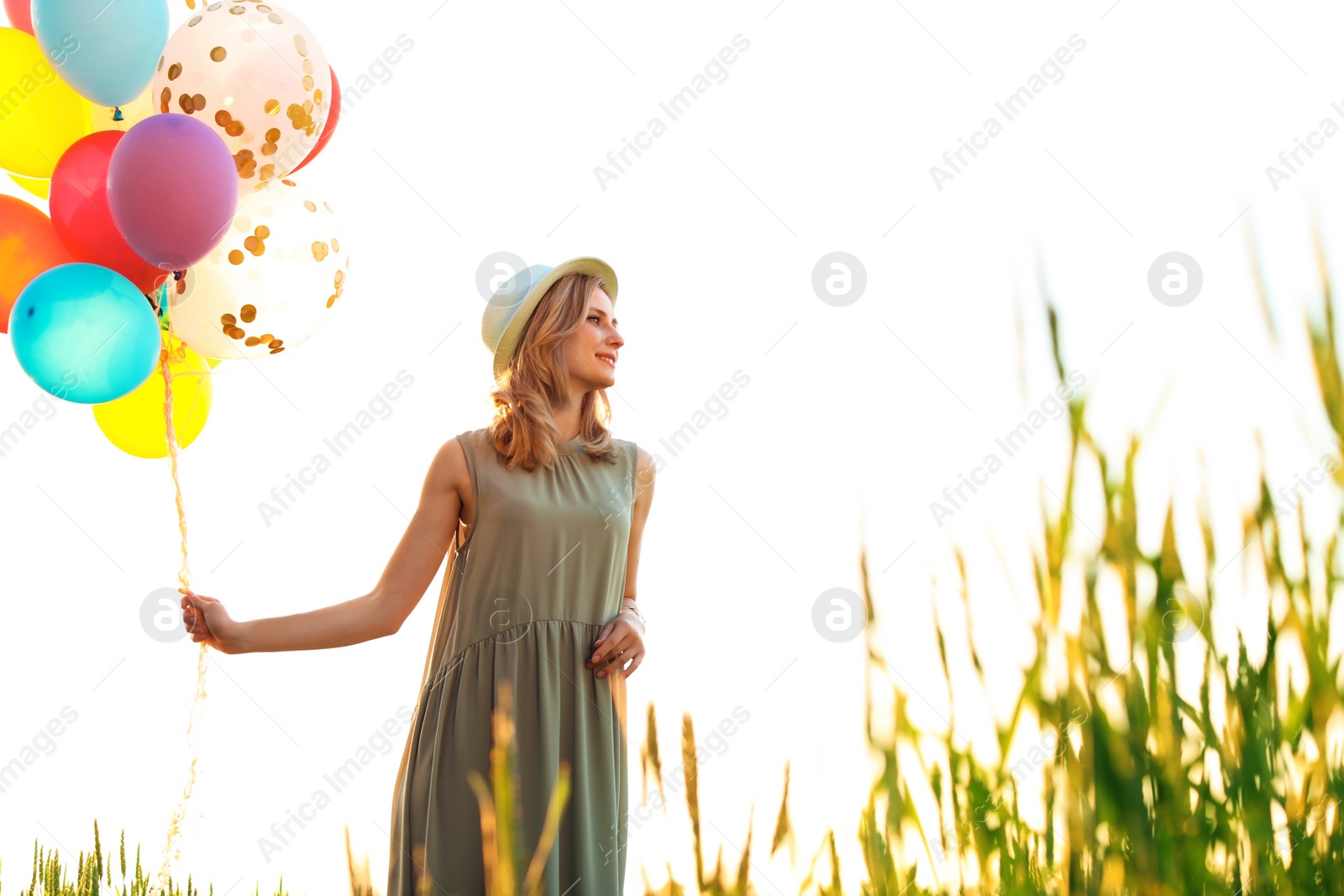 Photo of Young woman with colorful balloons outdoors on sunny day