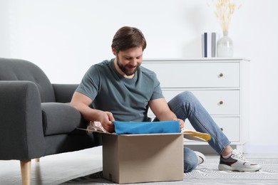 Photo of Happy man opening parcel at home. Internet shopping