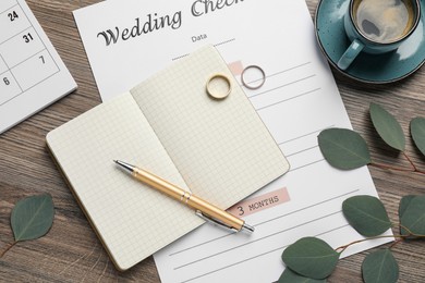 Flat lay composition with Wedding Checklist and planner on wooden table