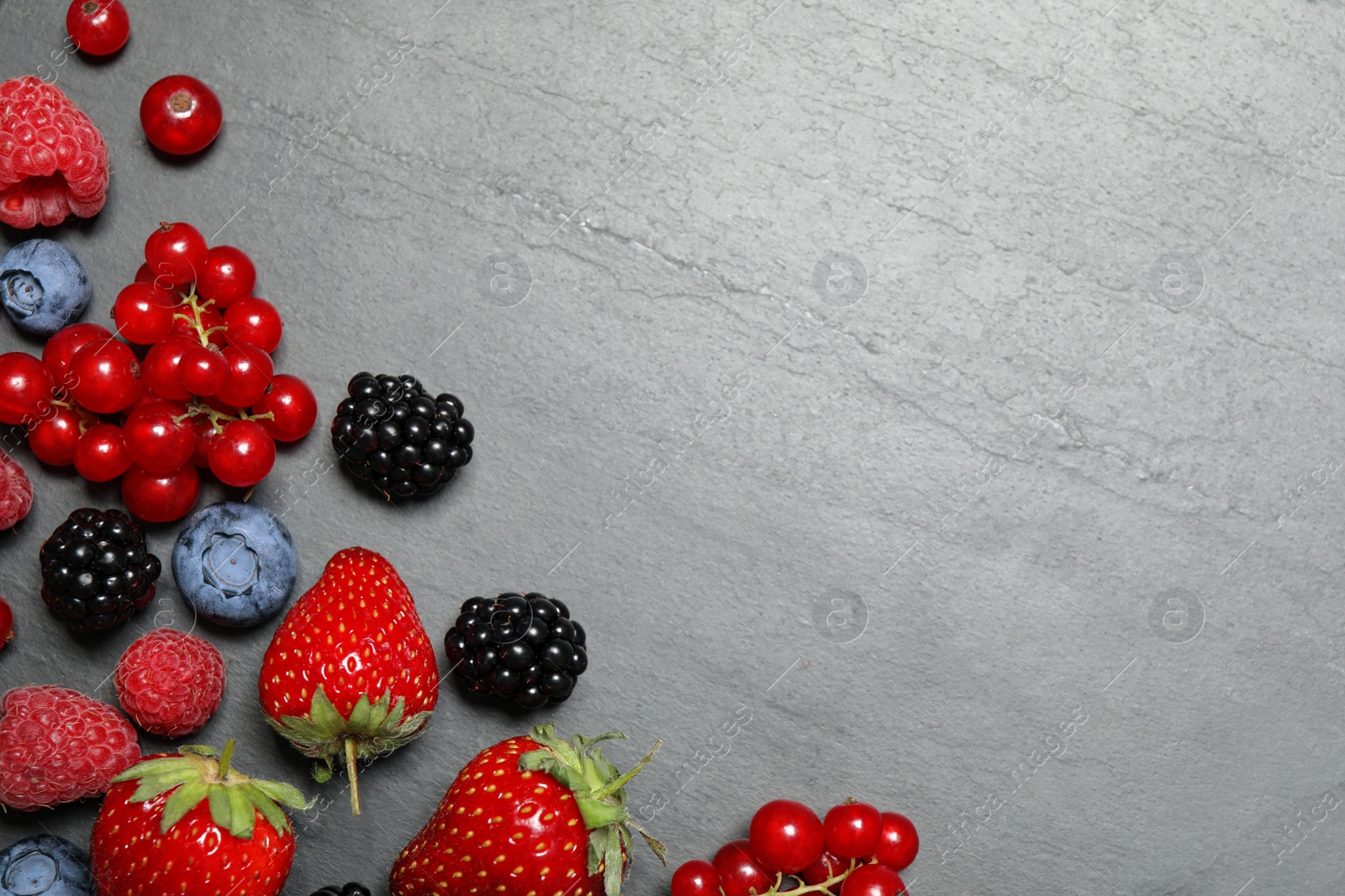 Photo of Different fresh berries on grey background, flat lay. Space for text