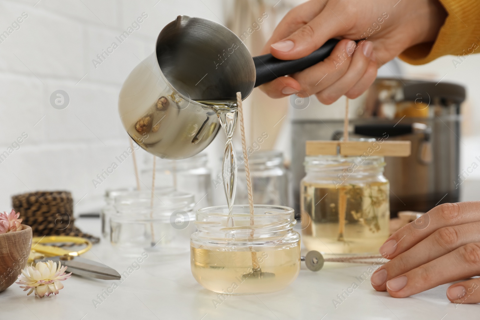 Photo of Woman making candles at white table, closeup