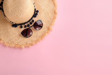 Stylish hat and sunglasses on color background, top view