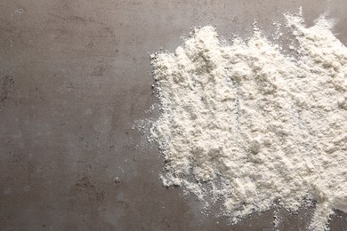 Scattered flour on grey textured table, top view. Space for text