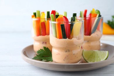 Photo of Fresh raw vegetable sticks with sauce on white wooden table