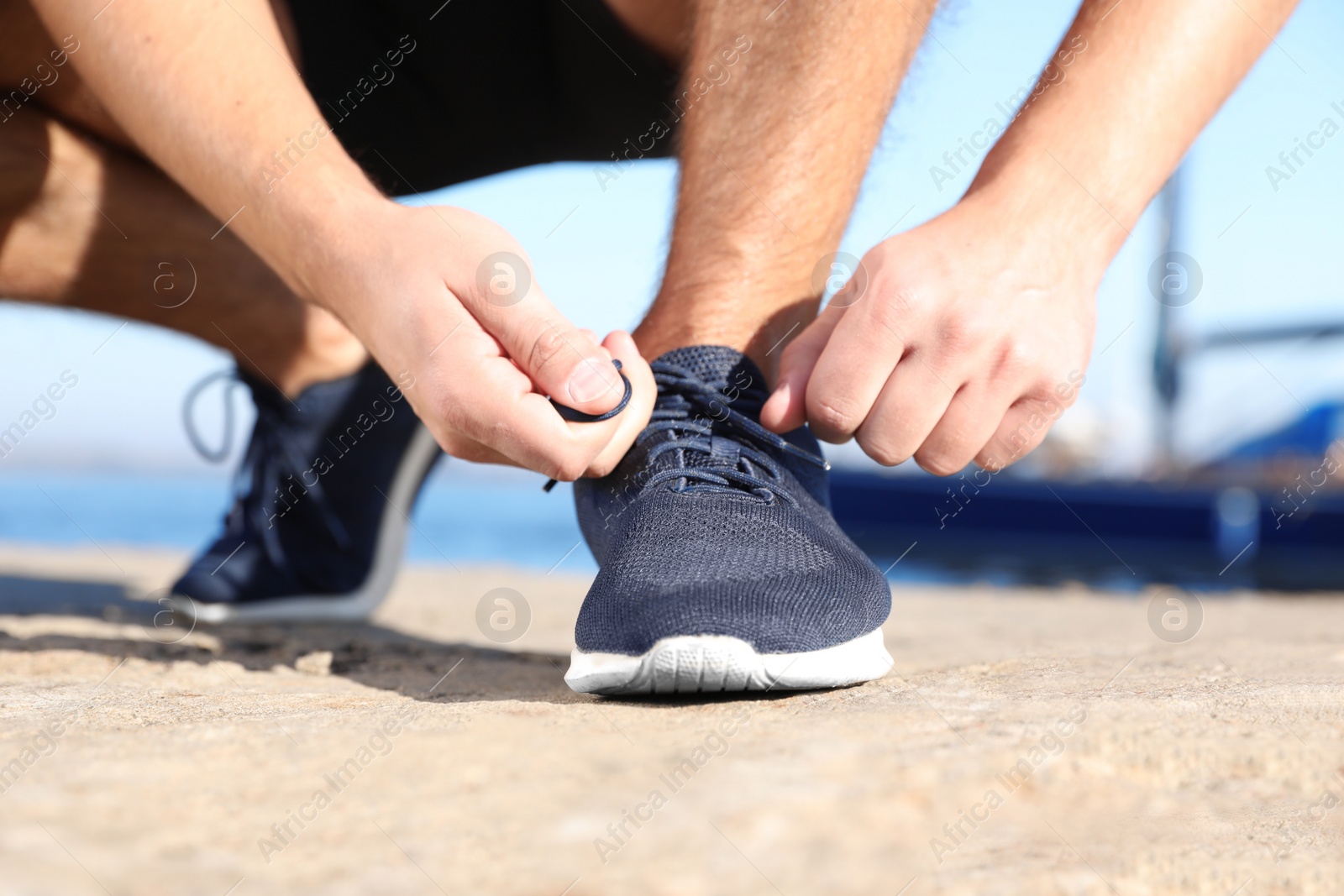 Photo of Sporty man tying shoelaces before running outdoors