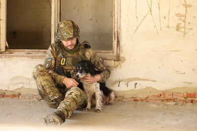 Photo of Ukrainian soldier sitting with stray dog in abandoned building. Space for text