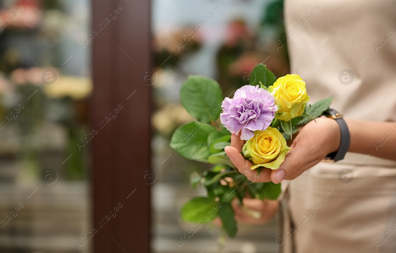 Photo of Female florist holding beautiful bouquet in flower shop, closeup