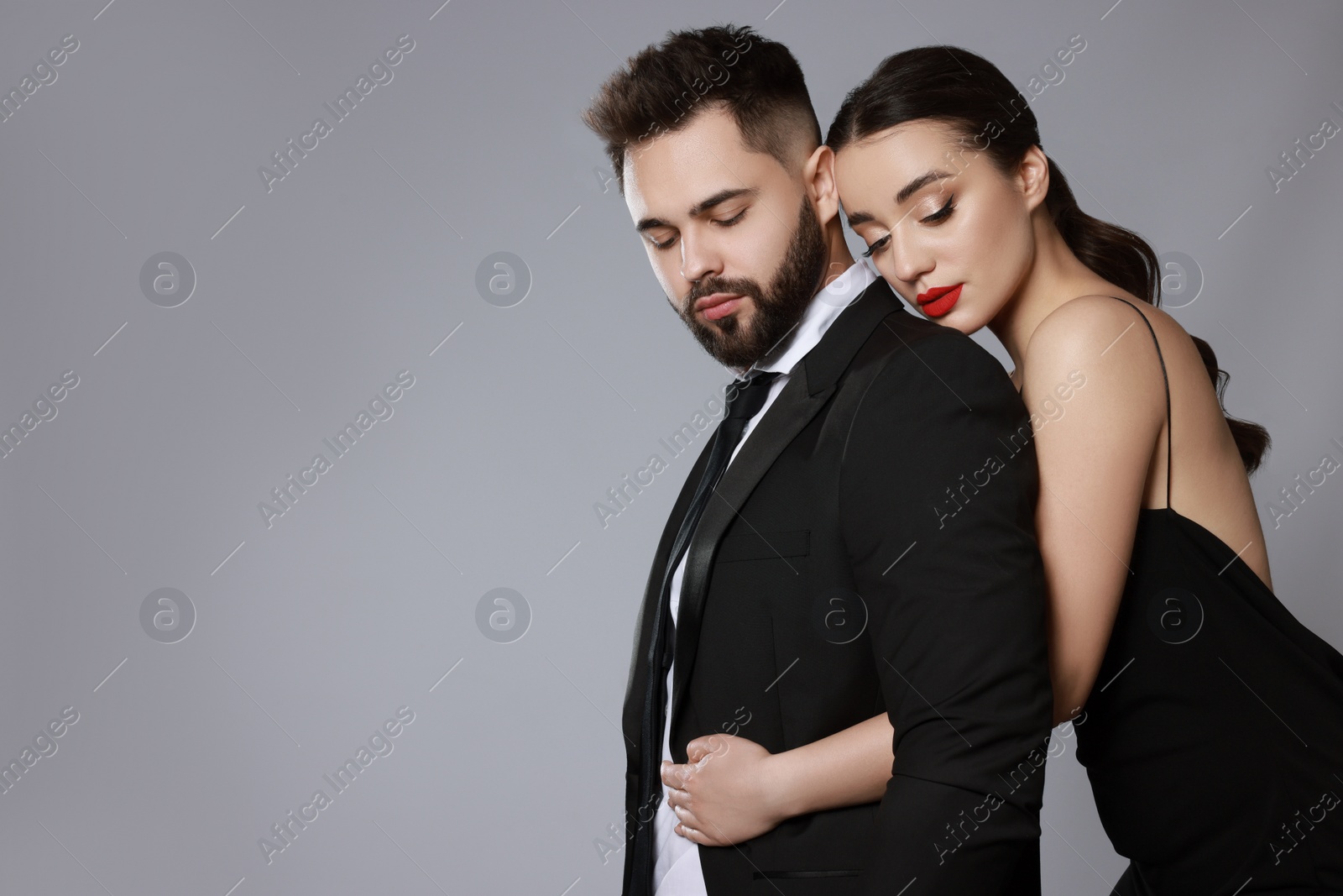 Photo of Handsome bearded man with sexy lady on grey background. Space for text