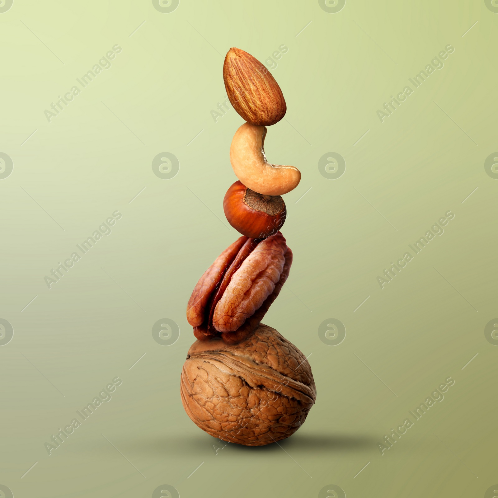 Image of Stacked different nuts on light green gradient background