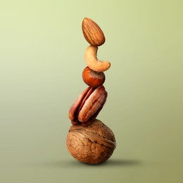 Image of Stacked different nuts on light green gradient background