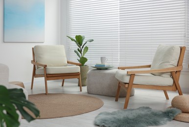 Photo of Comfortable beige armchairs, ottoman and houseplant in living room. Interior design