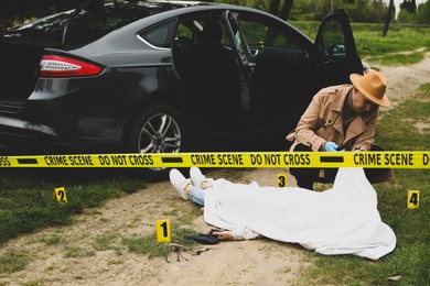 Photo of Investigator working at crime scene with dead body outdoors
