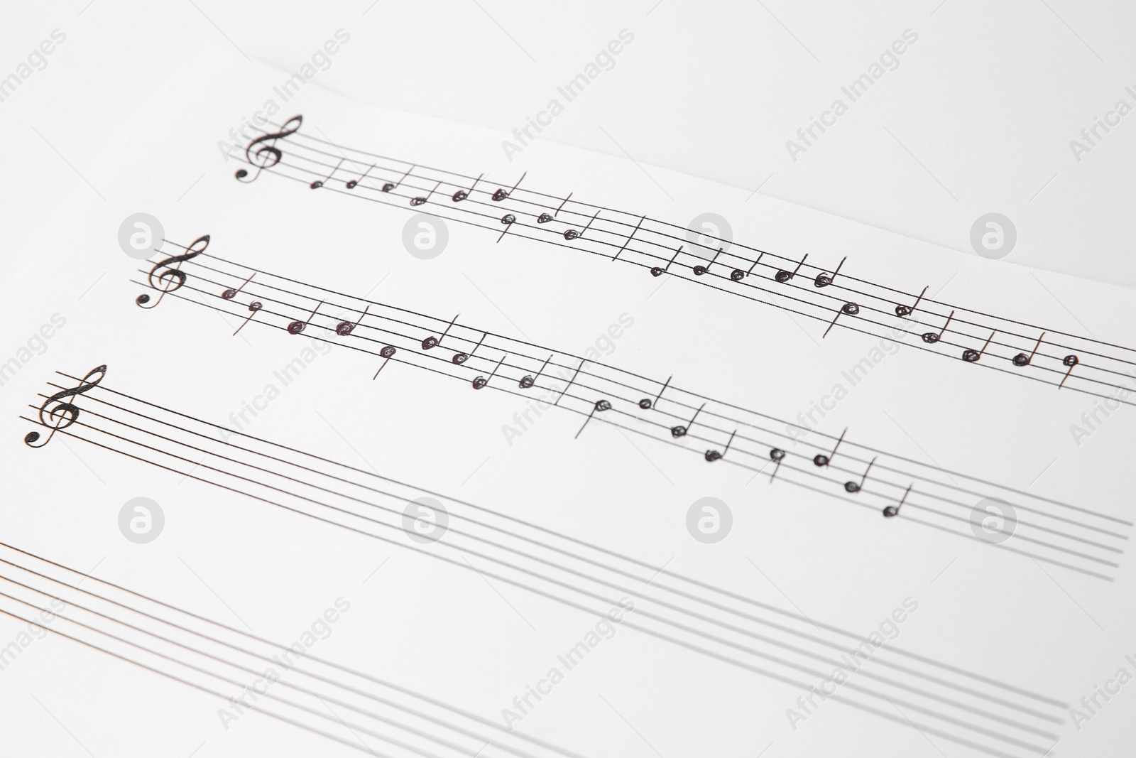 Photo of Sheet of paper with music notes on white background, closeup view