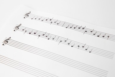 Photo of Sheet of paper with music notes on white background, closeup view