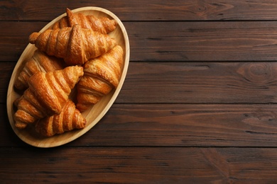 Photo of Tray with tasty croissants and space for text on wooden background, top view. French pastry