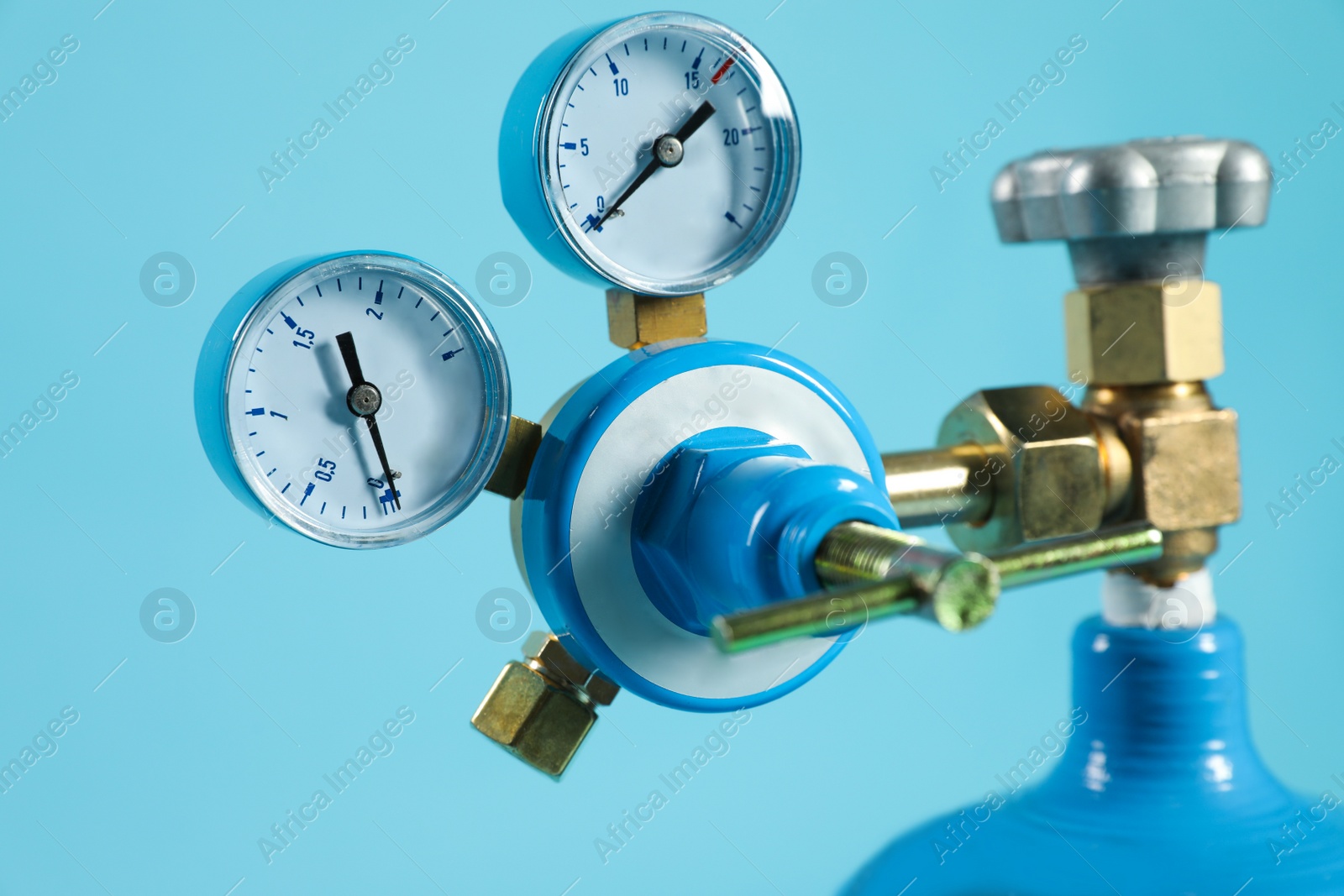 Photo of Pressure gauge of medical oxygen tank on light blue background, closeup