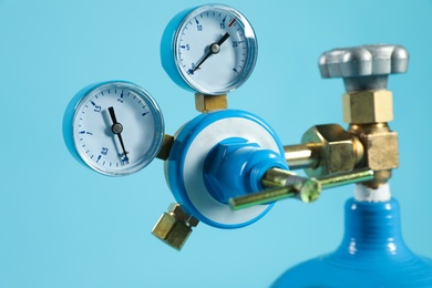 Photo of Pressure gauge of medical oxygen tank on light blue background, closeup