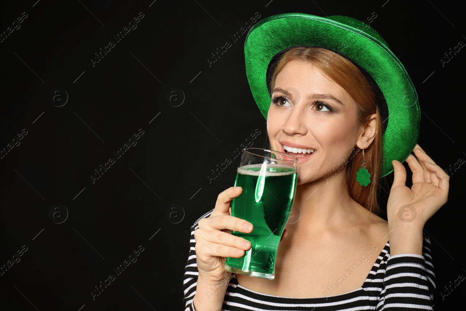 Photo of Young woman with green beer on black background. St. Patrick's Day celebration