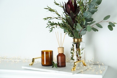 Photo of Reed air freshener with candle and bouquet on  marble tray