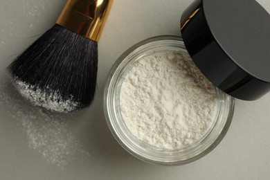Photo of Rice loose face powder and makeup brush on light grey background, flat lay