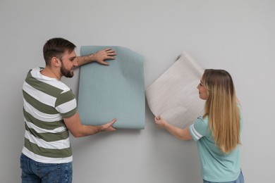 Photo of Young couple with new wall papers on light grey background