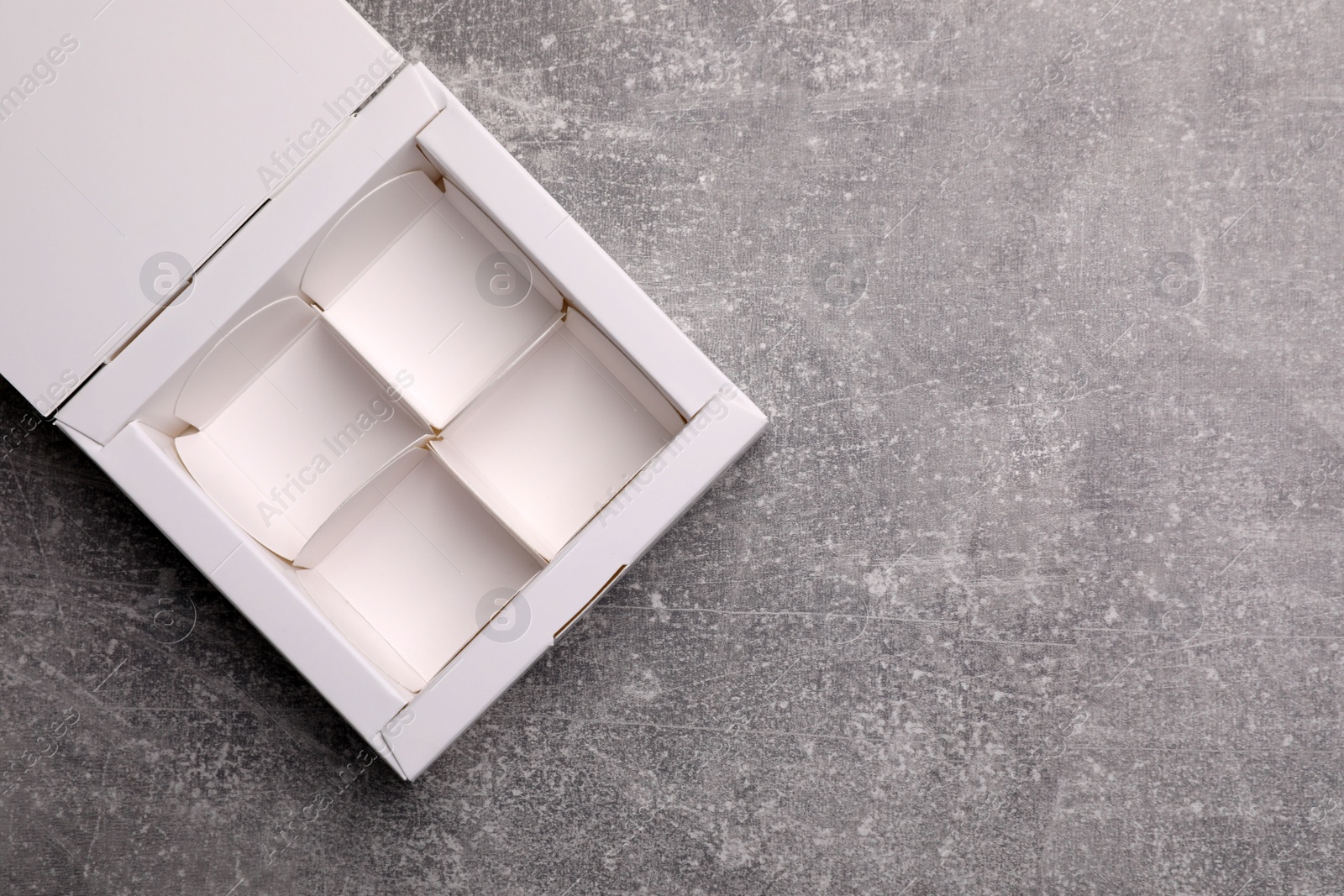 Photo of Empty white candy box on light grey table, top view. Space for text