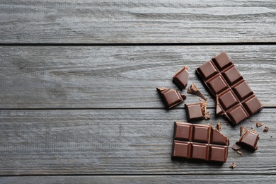 Photo of Tasty chocolate on wooden background, flat lay. Space for text