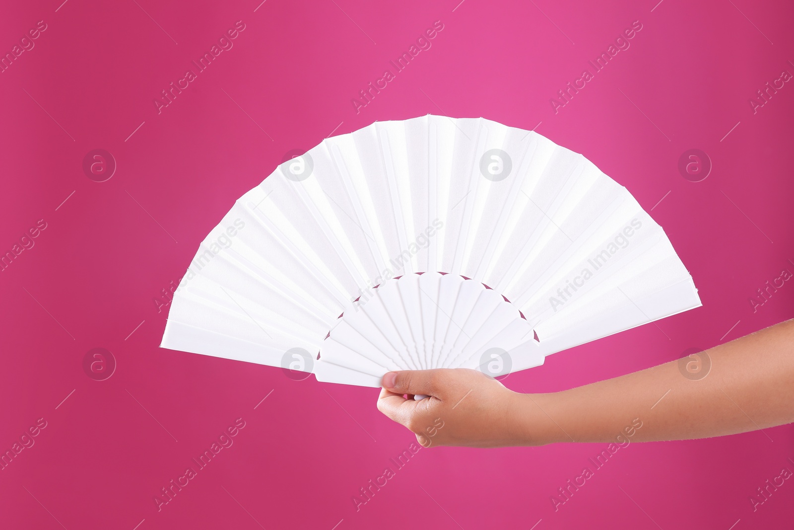 Photo of Woman holding white hand fan on pink background, closeup