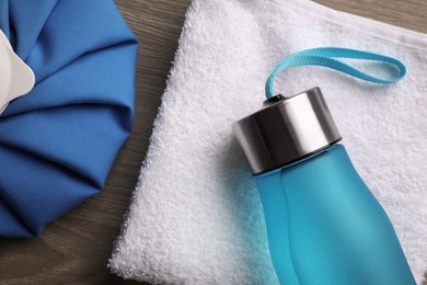 Bottle of water, cold compress and towel on wooden background, flat lay. Heat stroke treatment