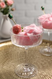 Photo of Glass with cotton candy and beautiful rose on golden tray