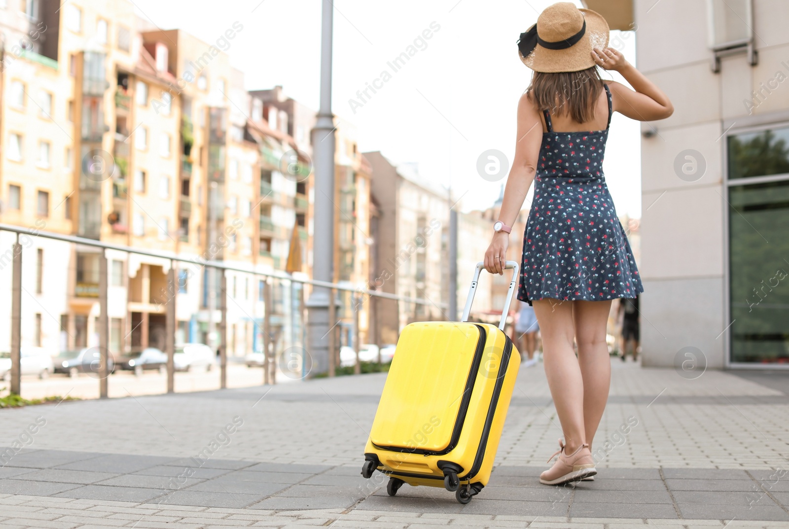 Photo of Young woman with yellow carry on suitcase outdoors